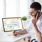 Image of a man on his phone with the JAV 25S Pro smart digital calendar on the desk showing his calendar.