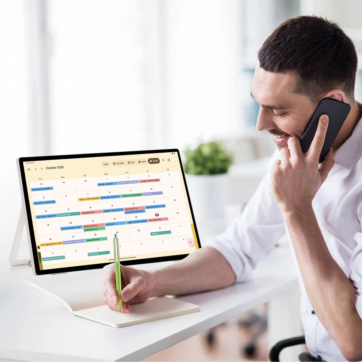 Image of a man on his phone with the JAV 25S Pro smart digital calendar on the desk showing his calendar.