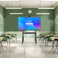 JAV H10S Pro smart board mounted on a mobile rolling stand at the front of an empty classroom with desks and chairs.