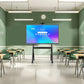 JAV H10S Pro smart board mounted on a mobile rolling stand at the front of an empty classroom with desks and chairs.