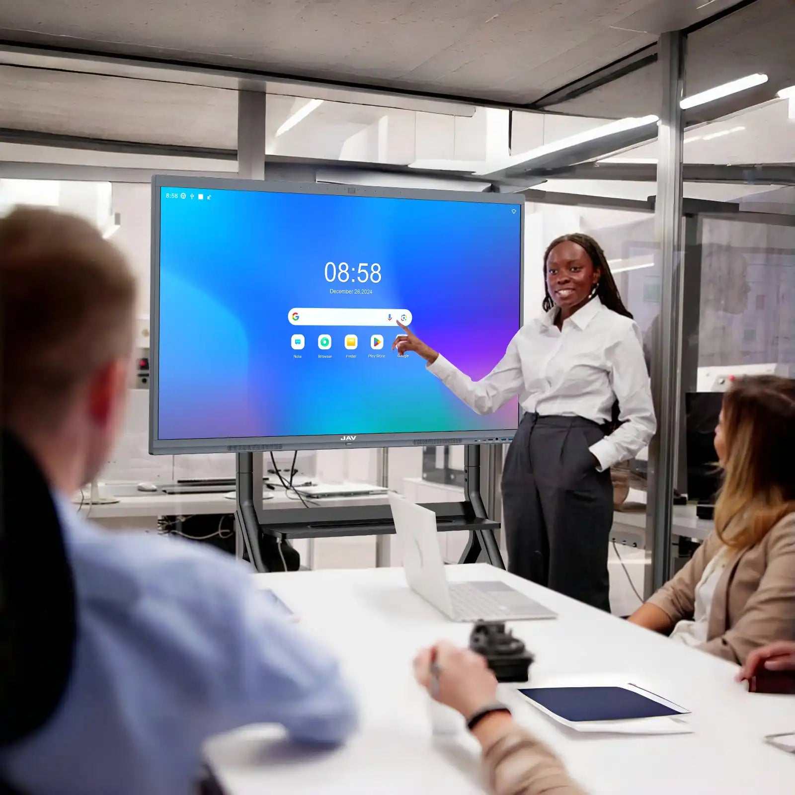 Woman leading a business presentation using a JAV H10S Pro smart board mounted on a rolling stand in an office environment.