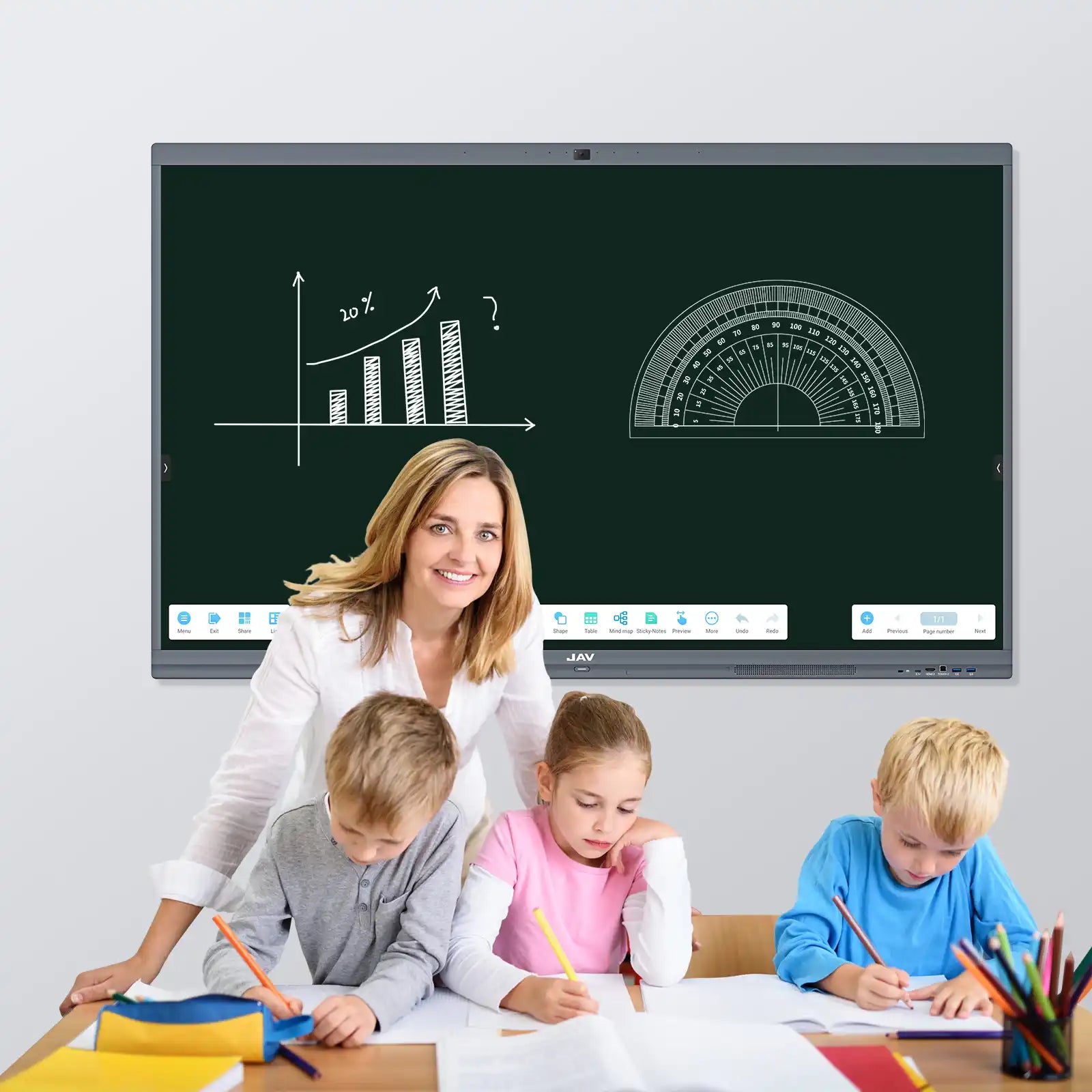 Teacher assisting young students at a desk, with a JAV H10S Pro interactive display showing educational math graphics in the classroom background.