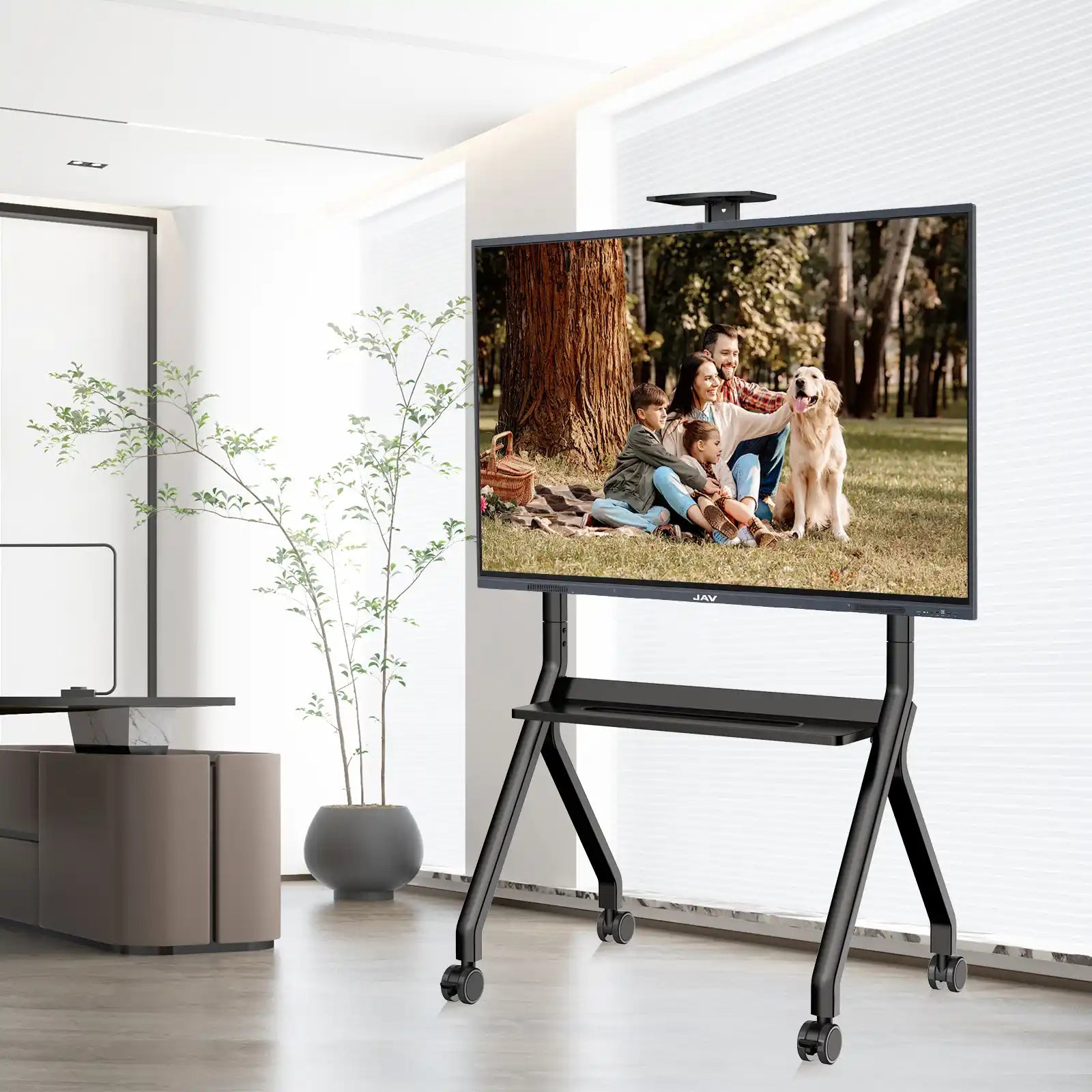 JAV smart board on a black mobile rolling stand displaying a family photo within a contemporary living room setting.