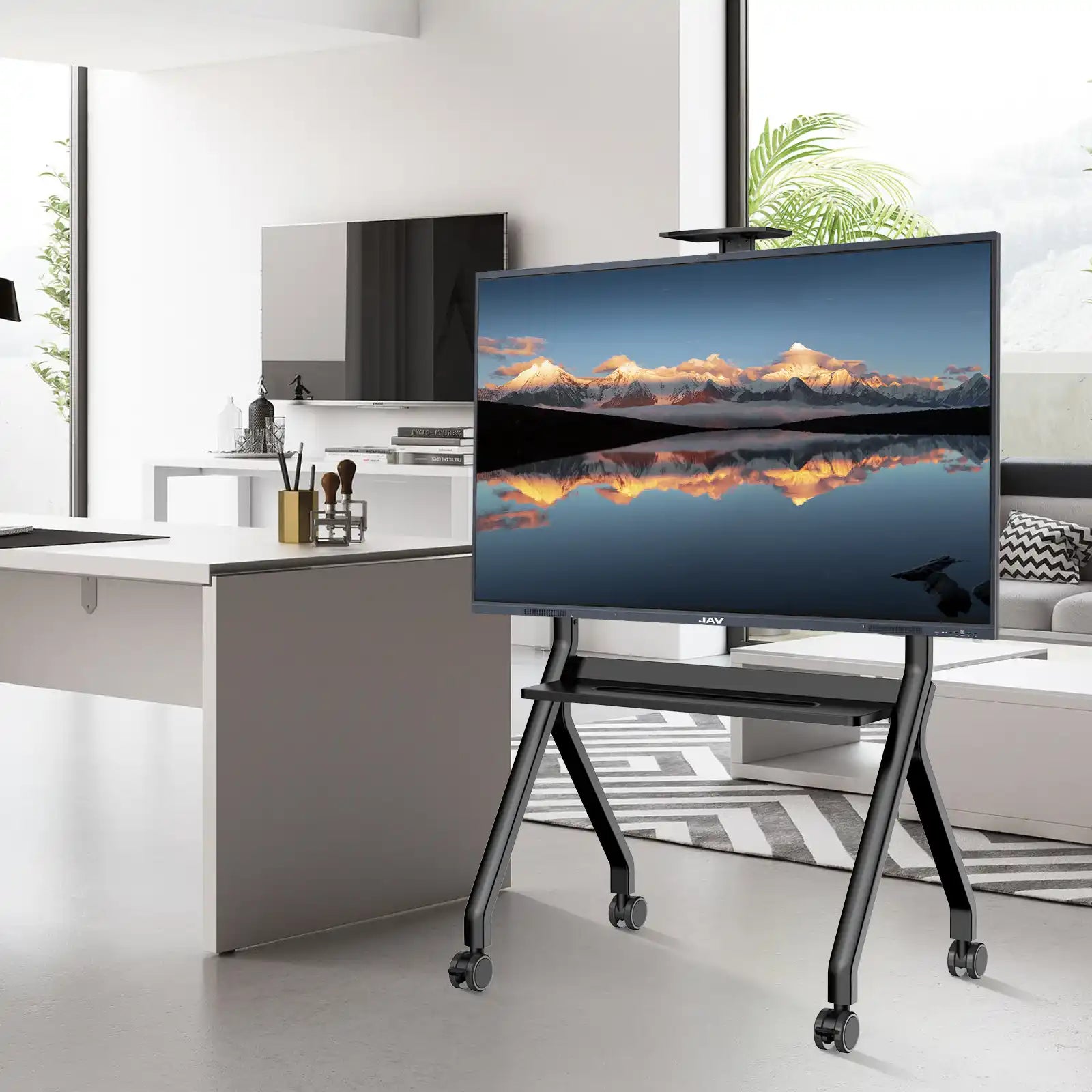 Large JAV smart board mounted on a black, mobile rolling stand with shelves and caster wheels, shown in a modern office environment.