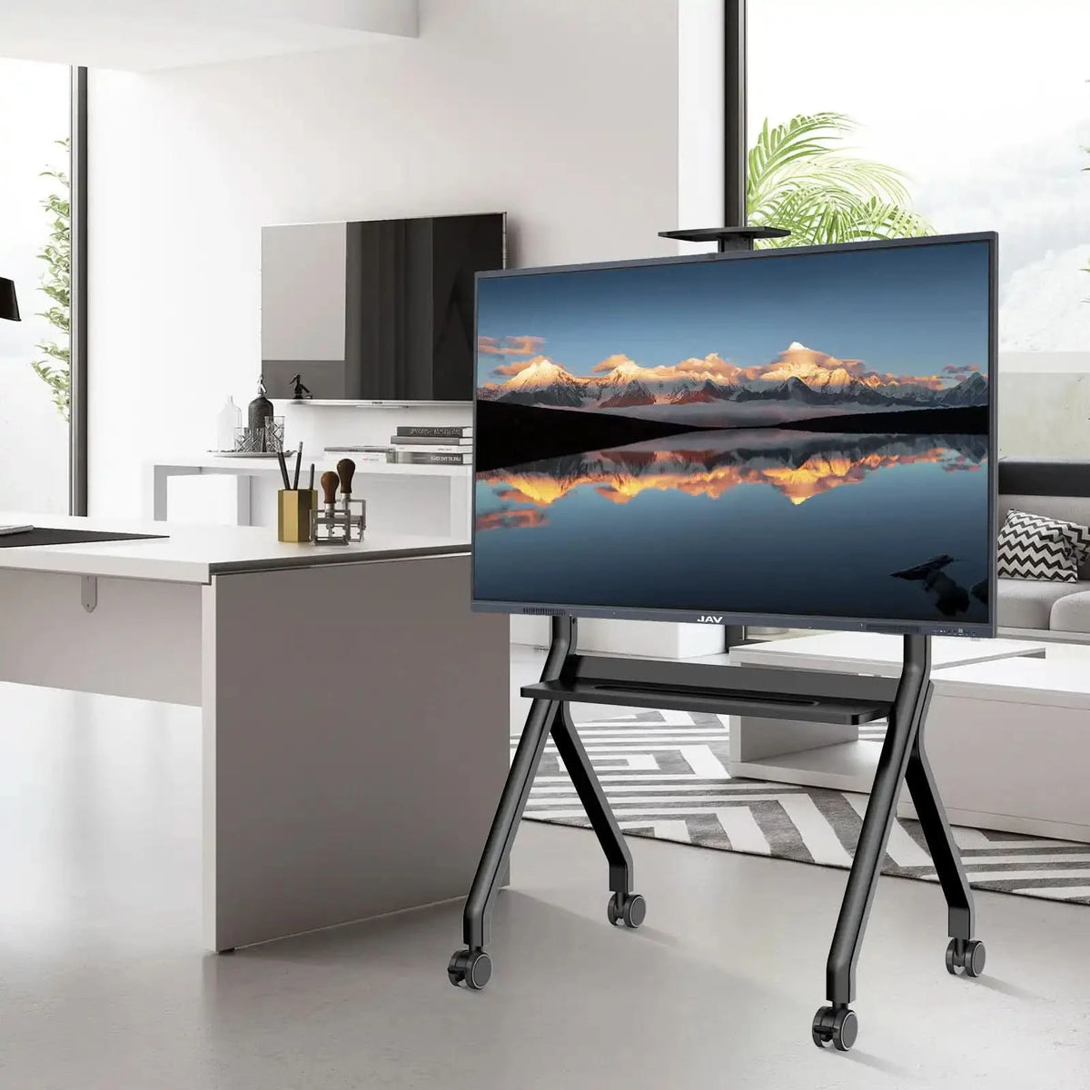 Large JAV smart board mounted on a black, mobile rolling stand with shelves and caster wheels, shown in a modern office environment.