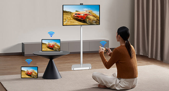 JAV smart board on a portable silver stand used for large-screen gaming, showing a racing game potentially mirrored from a nearby laptop or tablet.