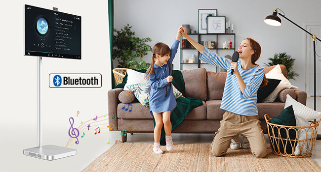 JAV smart board on a portable silver stand used for home entertainment activities like karaoke or live streaming, shown with a woman singing and a child dancing.